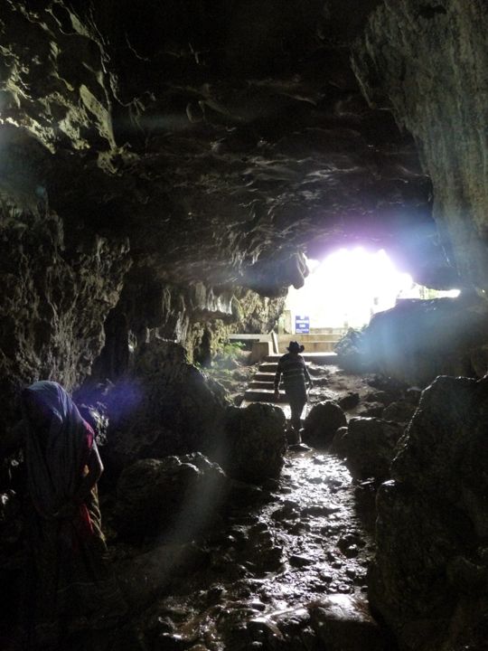 A person exploring the dark, mysterious depths of a cave in Meghalaya