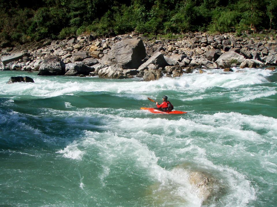 Travelers swimming in a clear natural pool at the base of a waterfall